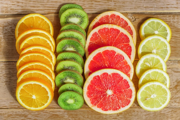 frame with slice of oranges lemons kiwi grapefruit pattern on wooden background copy space