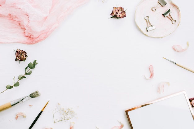 Frame with space for text of photo frame, pink blanket, eucalyptus branches and rose flowers on white background. Flat lay, top view