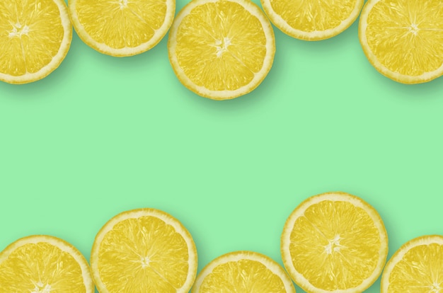 Frame of yellow lemon citrus slices on bright lime background