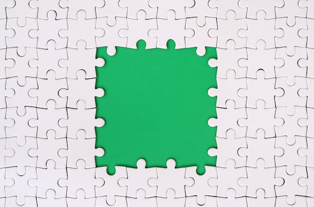 Framing in the form of a rectangle, made of a white jigsaw puzzle around the green space