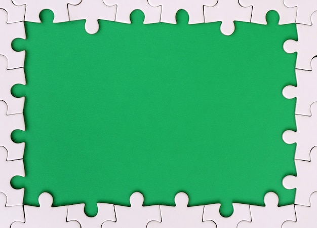 Framing in the form of a rectangle, made of a white jigsaw puzzle around the green space