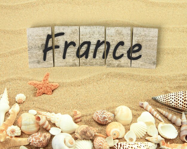 France on wooden board pieces with sea shells and sand