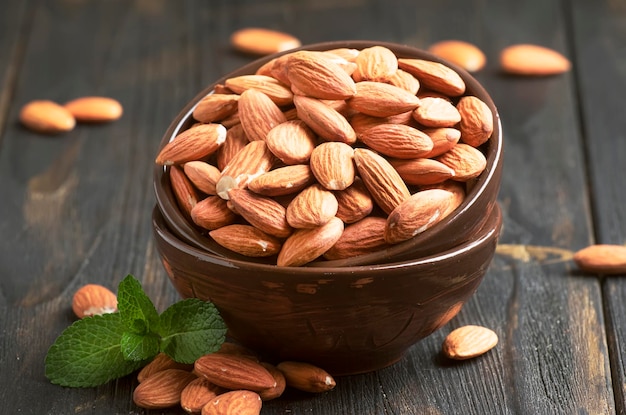 Freash almond in bowl on dark wooden kithcen table background selective focus