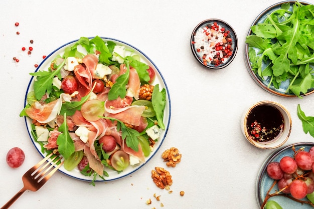 Freash grape salad with jamon blue cheese arugula nuts on white table background top view copy space