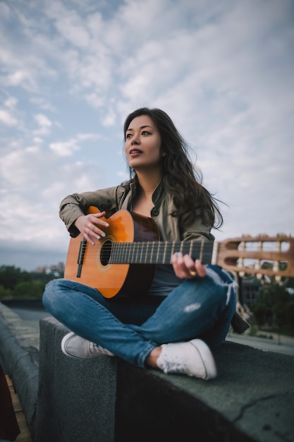 Free music. Female guitarist plays guitar on the street. Freedom, leisure, live concert, young bard and composer concept