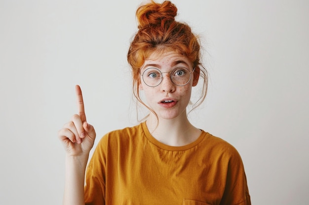 Free photo indoor shot of positive person in casual red tshirt points with index finger aside