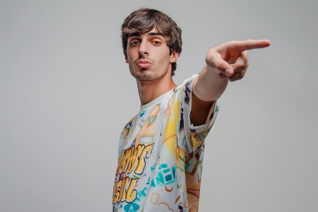 Free photo indoor shot of positive person in casual red tshirt points with index finger aside