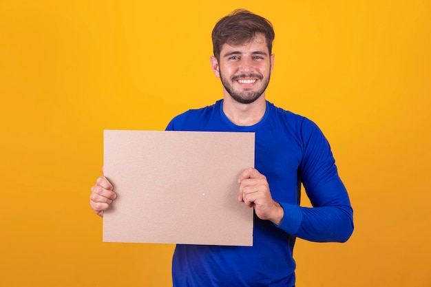 Free space for advertising Happy Caucasian man pointing at empty white board on yellow studio background mockup