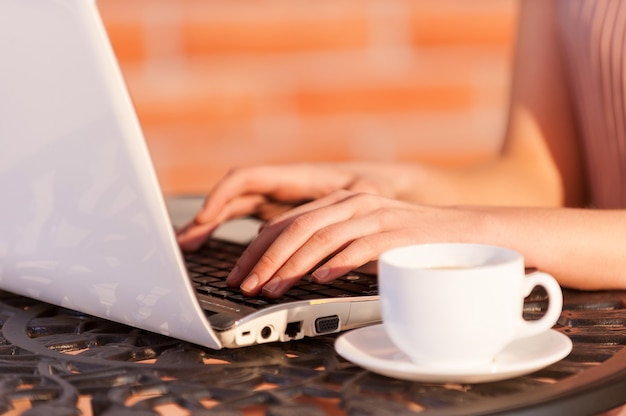 Free Wi-Fi zone. Cropped image of woman working at laptop while sitting at the outdoor cafe