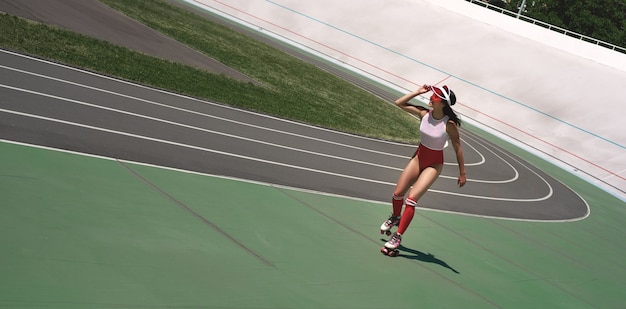 Freedom beautiful woman is rollerblading on the stadium smiling and looking at camera