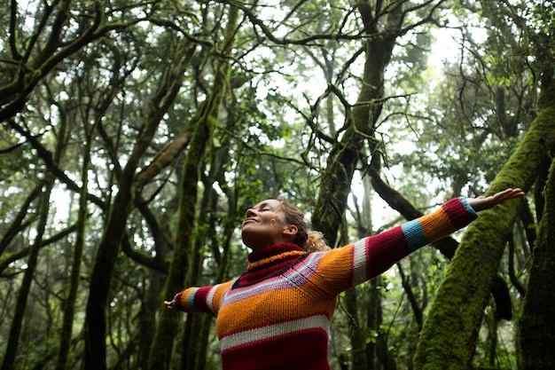 Freedom people enjoyng feeling with nature forest Woman outstretching arms in the green woods Leisure and ptrees protection Earth's day and life scenic place Tourist in travel amazing destination