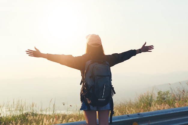 Freedom traveler woman standing with raised arms and enjoying a beautiful nature 