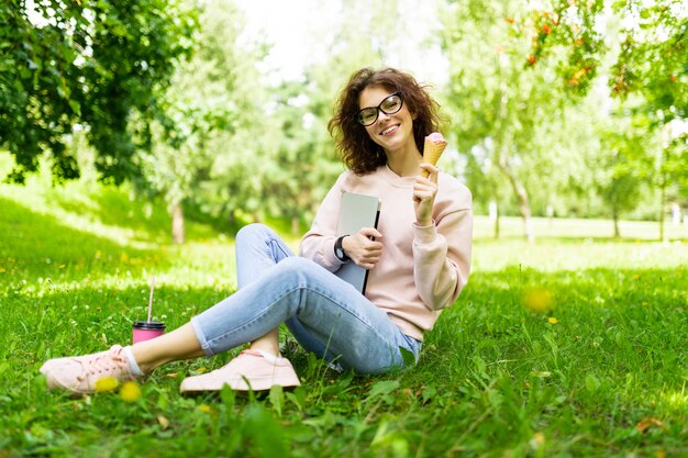 freelance concept. girl sitting on grass with laptop and ice cream