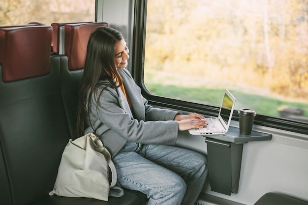 Freelance girl sitting on a train with a laptop. Modern technology and networking.