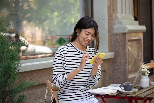 A freelance girl working with mobile phone and at laptop in an outdoor cafe