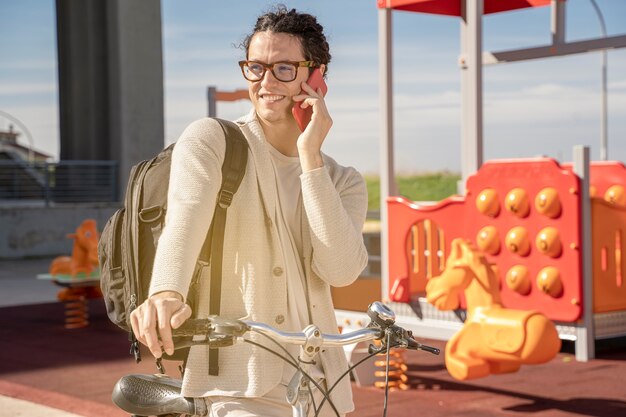 Freelance man using mobile phone on bicycle