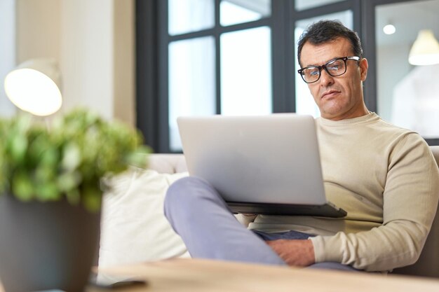 Freelance worker portrait of latin middle aged business man with eyeglasses working at home on