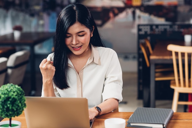 Freelance working woman with laptop computer, he gladly gets the results at coffee shop