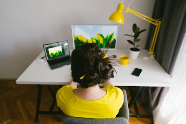 Freelancer designer woman working at home workplace white desk with yellow lamp