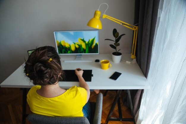 Freelancer designer woman working at home workplace white desk with yellow lamp