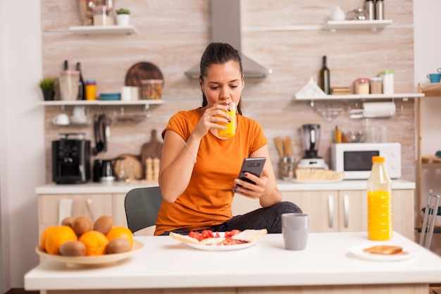 Freelancer drinking orange juice in the morning and doing shopping online