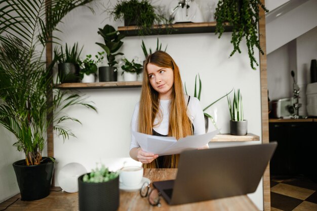 Freelancer girl working with laptop and documents in coffee shop