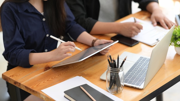 Freelancer working on digital tablet together in cafe