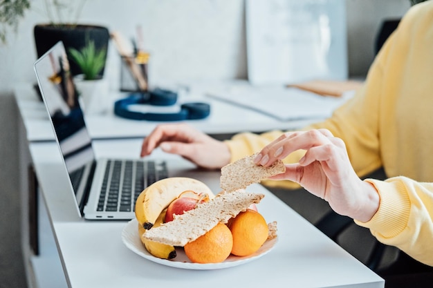 Freelancer young woman eating healthy food when working from home woman eating healthy grain snacks