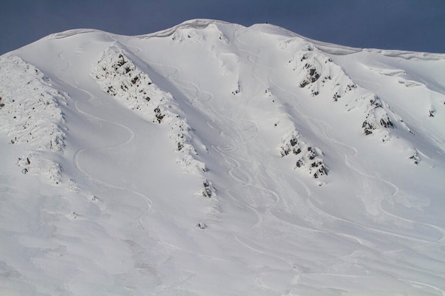 Freeride downhill on a steep and snowy slope next to a snow cornice in the high mountains