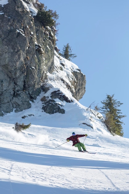 Freeride skier skiing downhill during sunny day in high mountains