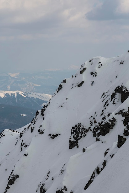 A freerider skier descends a steep mountain slope among rocks