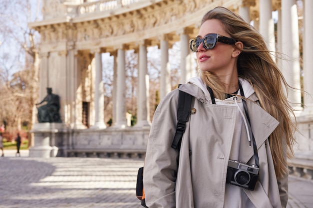 Freespirited young woman with camera admiring old building