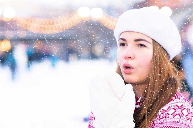 Freezing woman, a young beautiful frozen girl in the snow suffers from cold icy weather, shakes, trembles outside on an icy snowy day, low temperature, breathes with her hands, tries to keep warm