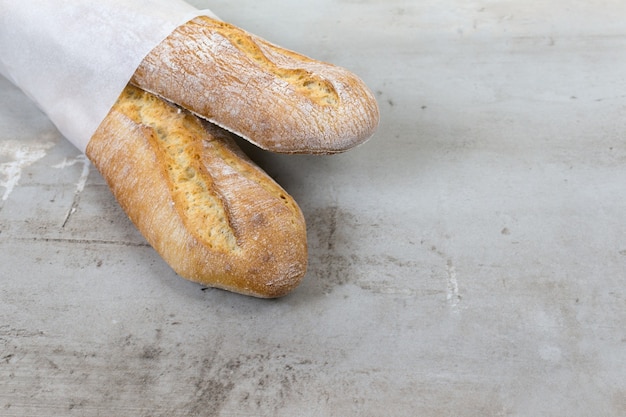 french baguettes baked bread on grey stone table background ecofriendly paper packaging