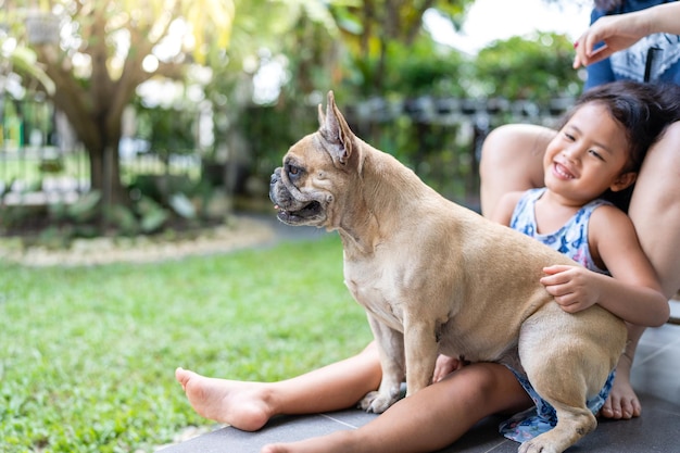 French bulldog sitting on little girl's lap and smiling at camera.