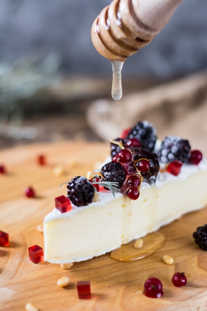 French cheese brie, camambert with honey, marmalade and pine nuts on wooden cheese board. 