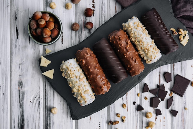 French dessert eclairs or profiteroles with different chocolate icing on a black stone plate