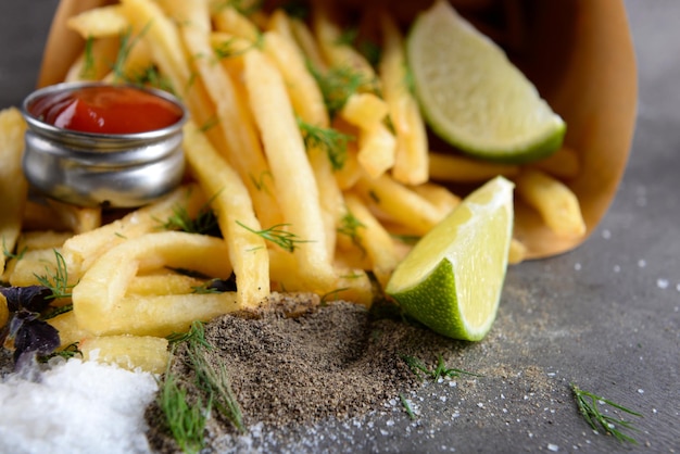 French fries in bag with sauce lime and spice on table