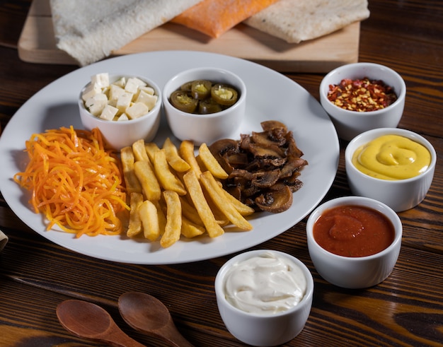 French fries, carrots, cucumbers served on a table with different sauces