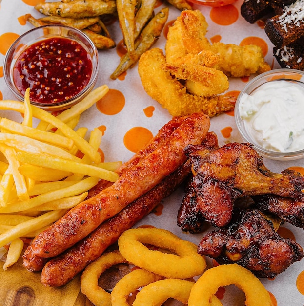 french fries potatoes with onion rings sausages croutons and spicy chicken legs