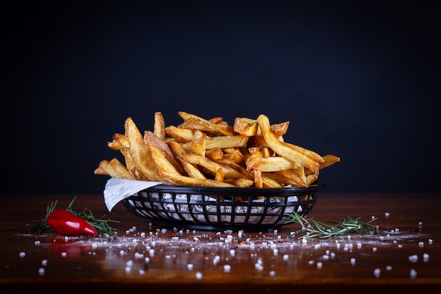 French fries served on a basket cutting board on a black wooden table Rustic french fries hand made