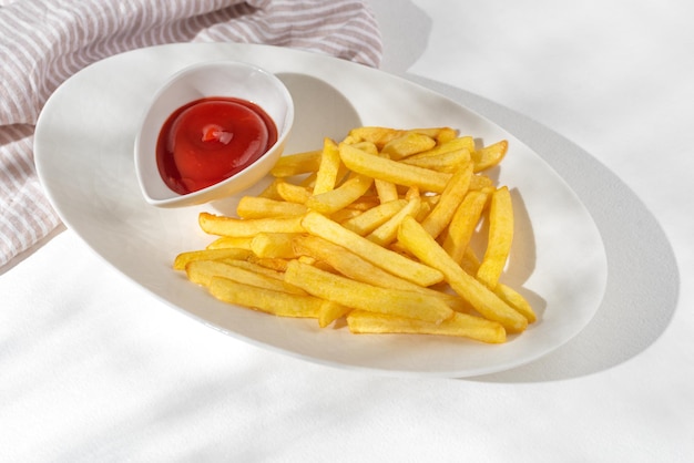 French fries on white plate with ketchup on a white plate