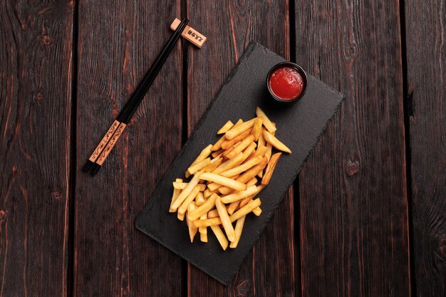 French fries with ketchup on dark wooden background top view fast food and unhealthy eat concept