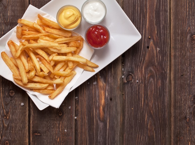 Photo french fries with sauce on wooden table.