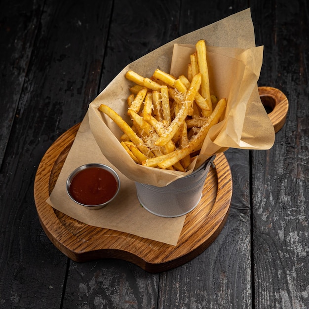 French fries with tomato sauce on a dark wooden table