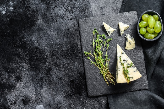 French Gorgonzola cheese with grapes. Black background. Top view. Copy space.