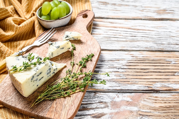 French Gorgonzola cheese with grapes. White wooden background. Top view. Copy space.