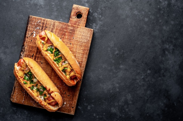 french hot dogs baked with cheese and mustard on a stone background