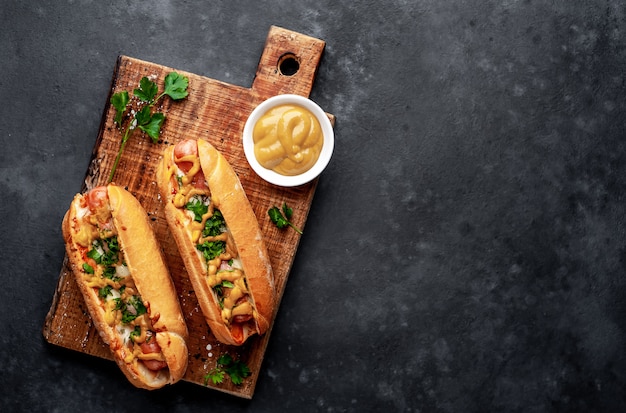 french hot dogs baked with cheese and mustard on a stone background