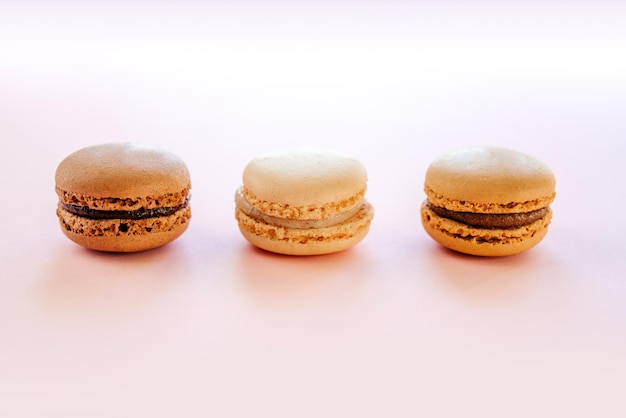 French macarons or macaroons with vanilla mocha and chocolate flavour on pink background